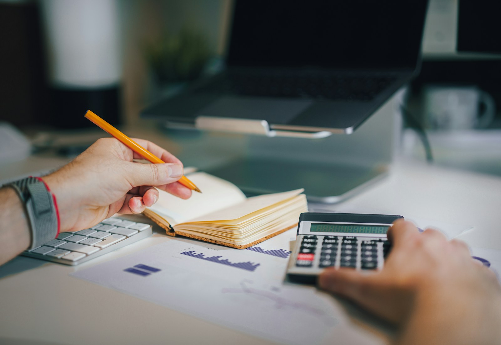 Clean workspace with calculator, notebook, financial papers, and laptop for QuickBooks bookkeeping support